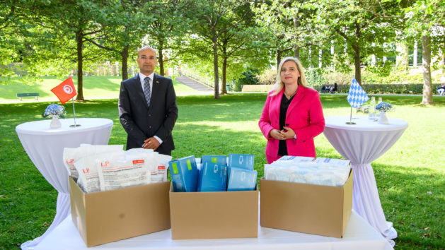 Staatsministerin Melanie Huml, MdL (rechts), übergibt im Hofgarten in München eine Spende von medizinischen Material an den tunesischen Konsul Mohsen Sebai (links).